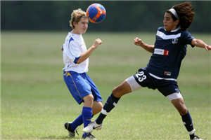 Two Boys From Opposing Teams Going For The Ball